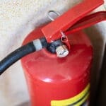 Wallmounted extinguisher with details. Industrial safety equipment showing wear and gauges
